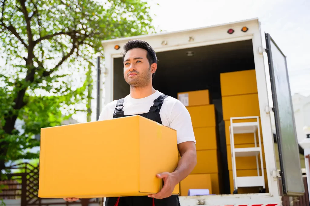 A worker carrying a box from the moving truck