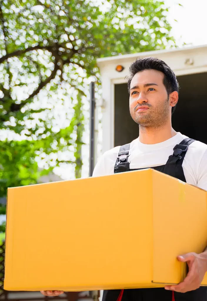 image of a worker carrying a box from the moving truck